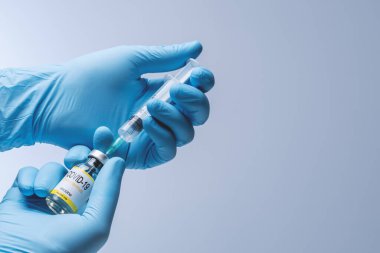 Doctor in blue latex gloves fill in syringe with vaccine from glass vial. Vaccination, immunization, treatment to Covid 19 Corona Virus infection. Healthcare And Medical concept.