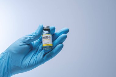Doctor in blue latex gloves holding glass vial with medicine. Vaccination, immunization, treatment to Covid 19 Corona Virus infection. Healthcare And Medical concept.