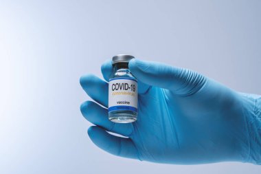 Doctor in blue latex gloves holding glass vial with medicine. Vaccination, immunization, treatment to Covid 19 Corona Virus infection. Healthcare And Medical concept.