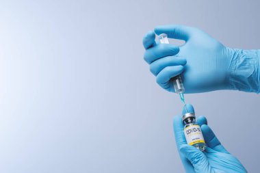 Doctor in blue latex gloves fill in syringe with vaccine from glass vial. Vaccination, immunization, treatment to Covid 19 Corona Virus infection. Healthcare And Medical concept.