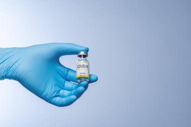Doctor in blue latex gloves holding glass vial with medicine. Vaccination, immunization, treatment to Covid 19 Corona Virus infection. Healthcare And Medical concept.