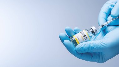 Doctor in blue latex gloves fill in syringe with vaccine from glass vial. Vaccination, immunization, treatment to Covid 19 Corona Virus infection. Healthcare And Medical concept.