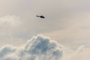 Dramatik gökyüzü arka planında uçan helikopter.