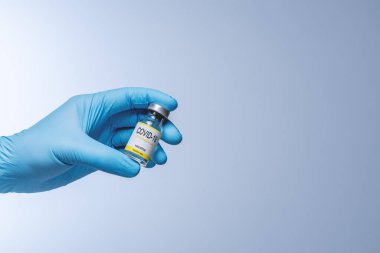 Doctor in blue latex gloves holding glass vial with medicine. Vaccination, immunization, treatment to Covid 19 Corona Virus infection. Healthcare And Medical concept.