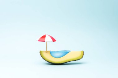 Avokado meyvesi ve güneş şemsiyesinden yapılmış yüzme havuzu. Yaratıcı asgari tropikal kavram.