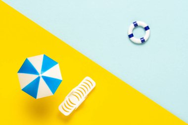 Güneş şemsiyesi ve denizi olan oyuncak plajı. Tatilde asgari konsept. Tatil arkaplanı düzleştirildi.