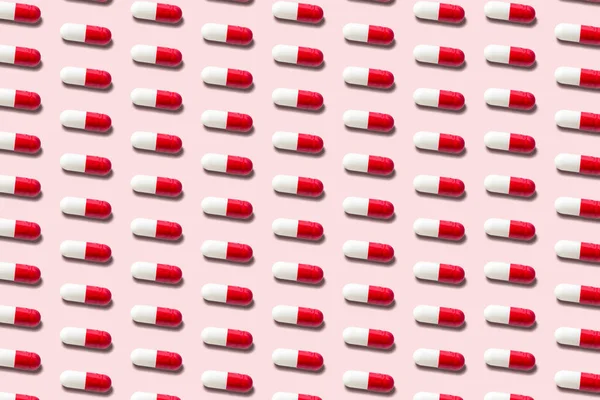 Creative pattern with red pills on pink background. Minimal medical concept.