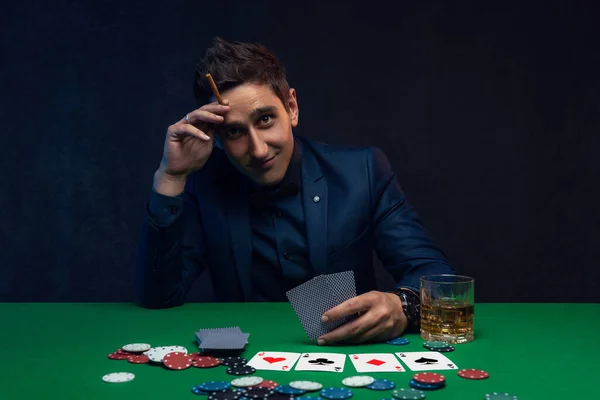 A wealthy man drinking brandy and playing poker with the excitement in a casino.