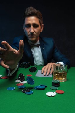 Poker oyuncusu kumarhanede yeşil masaya fiş atıyor..