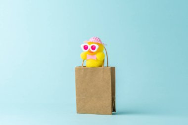 Cute chicken in shopping bag on blue background. Creative minimal shopping concept.