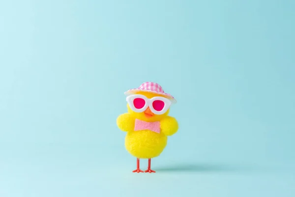 Funny chicken with hat on blue background. Spring Easter minimal concept.