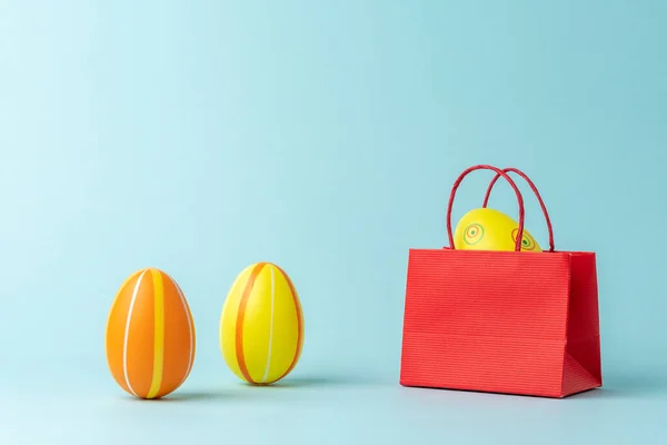 Easter egg in shopping bag on blue background. Easter minimal concept. Creative Happy Easter or spring layout.