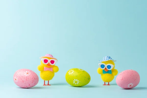 Funny chicken dolls with colorful Easter eggs. Minimal Easter concept.