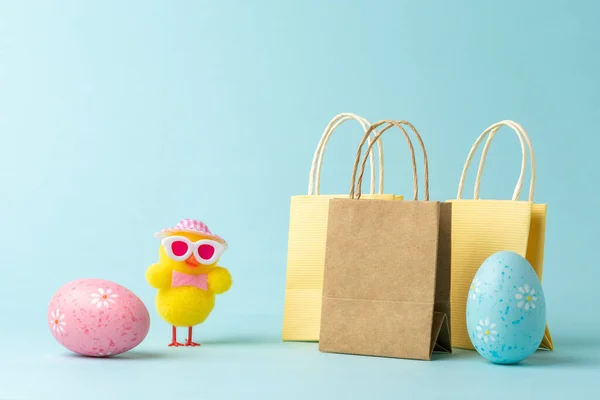 Chicken with Easter eggs and shopping bags on blue background. Easter minimal concept. Creative Happy Easter or spring layout.