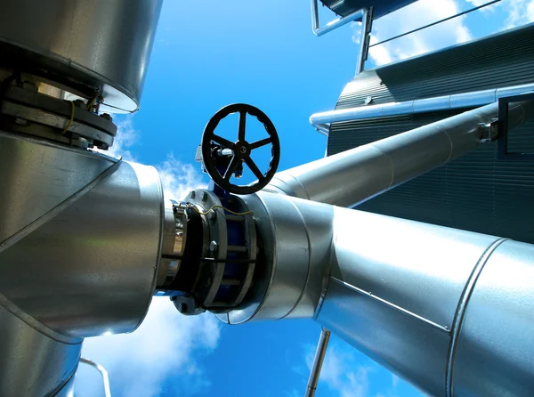 Industrial zone, Steel pipelines and valves against blue sky Stock Image