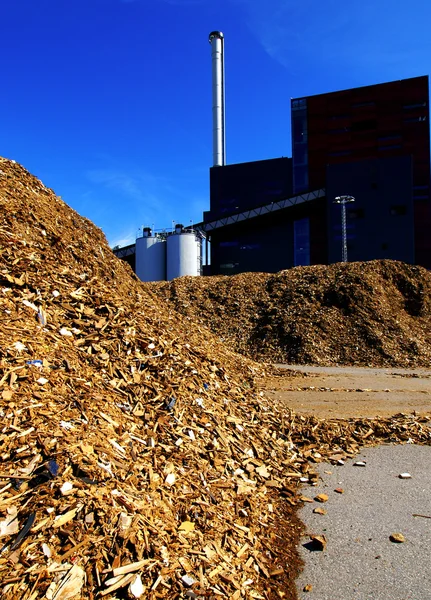 Bio power plant with storage of wooden fuel against blue sky Stock Image