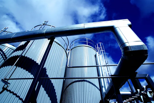 Zona industriale, tubazioni e valvole in acciaio contro il cielo blu — Foto Stock