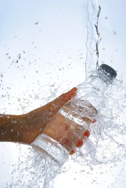 Botella de agua en la mano, en un spray de gotas de agua — Foto de Stock