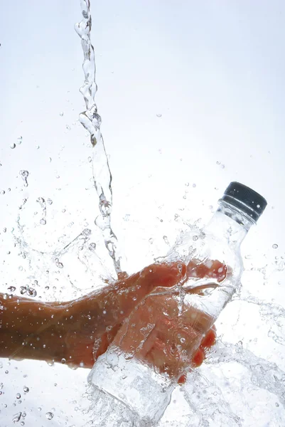 Botella de agua en la mano, en un spray de gotas de agua — Foto de Stock