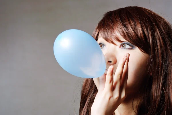 Portrait of middle aged woman blowing a balloon against a grunge — Stock Photo, Image