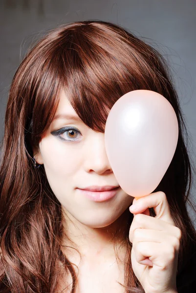 Portrait of middle aged woman blowing a balloon against a grunge — Stock Photo, Image