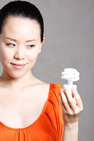 Улыбающаяся женщина дает энергосберегающую лампочку, изолированную на белом — стоковое фото