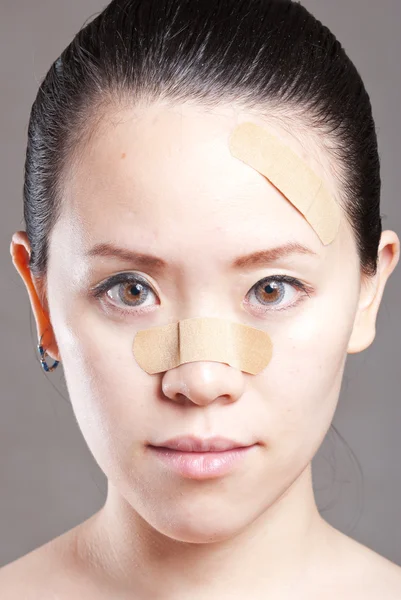 Woman putting a band-aid on her arm isolated over white — Stock Photo, Image