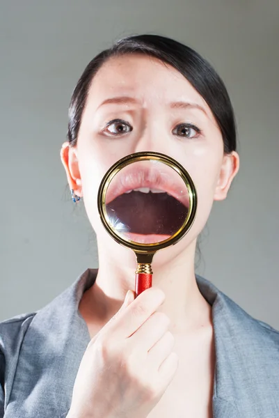 Portrait of lovely young woman with magnifying glass showing her — Stock Photo, Image