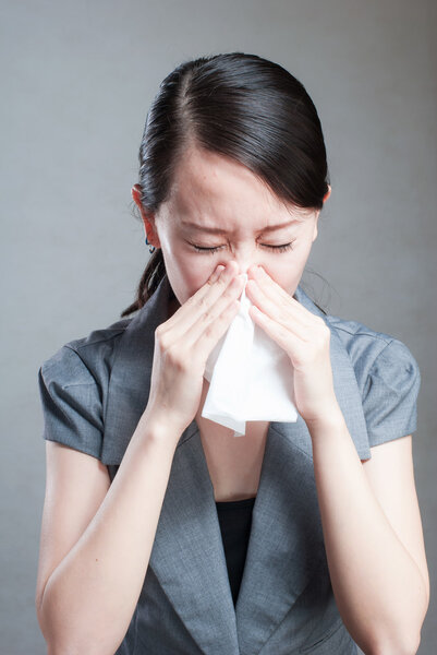У молодой женщины простуда и она держит салфетку.
