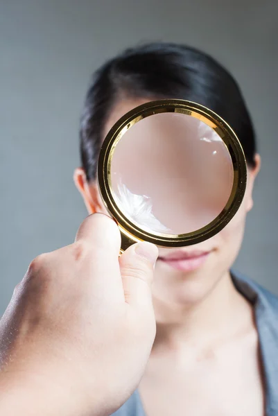 Portrait of lovely young woman with magnifying glass showing her — Stock Photo, Image