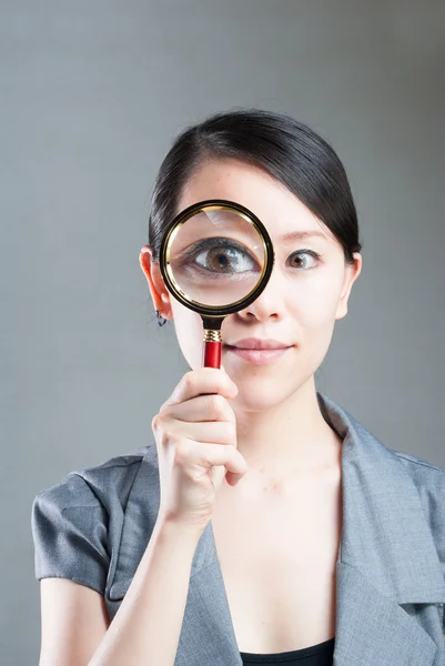 Portrait of lovely young woman with magnifying glass showing her Stock Image
