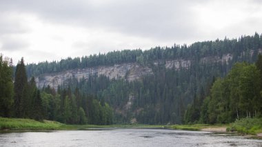 Ağaçlı kayaların arkasındaki yeşil ormanların arasındaki nehir.