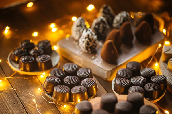 Assorted chocolates on wooden table with garland — Stock Photo, Image