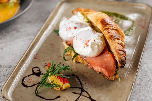 Круассан с яичницей и лососем на завтрак — стоковое фото