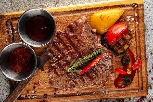 Gegrilde biefstuk met sauzen op houten plank — Stockfoto