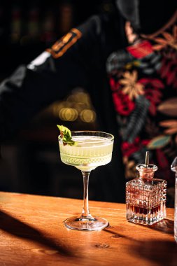 Barmen süslü bardakta kokteyl yapıyor.