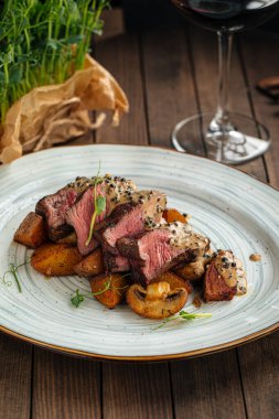 Biftek madalyonları patates ve mantarla servis edilir.