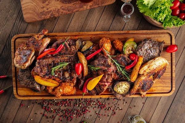 Surtido de carne a la parrilla en tablero de servir de madera — Foto de Stock