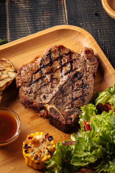 Closeup on grilled beef steak set with salad and sauce