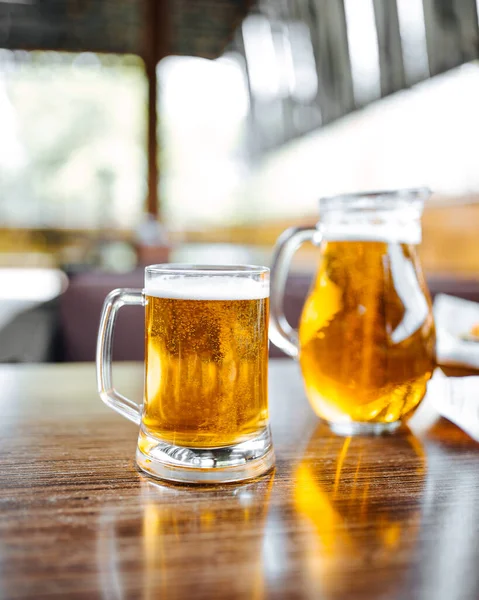 Glass mug and jug of beer on the table — Stock Photo, Image