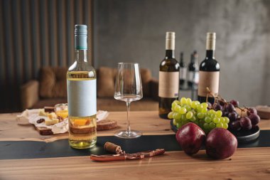 Ahşap masada aperatifli çeşitli şarap şişeleri ve bardaklar.