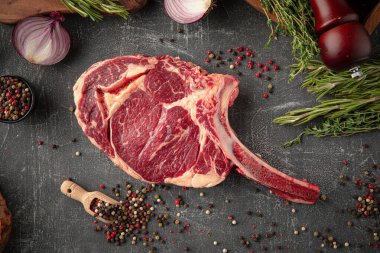 Gri dekore edilmiş arka planda çiğ Amerikan baltası bifteği.