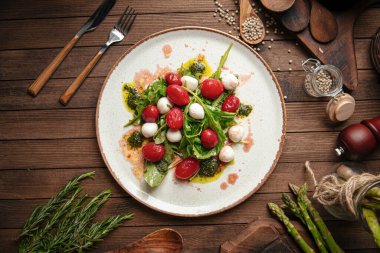 Çeri domates ve ahşap arka planda mozarella peynirli salata.