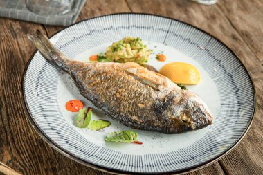 Ahşap arka planda ızgara gurme balığı tabağına yakın plan.