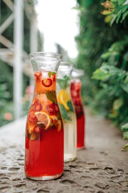 Bahçede üç bardak taze çilek ve meyve limonatası.