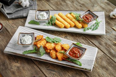 Tahta arka planda nugget ve peynirli kızarmış aperatifler.