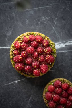 İki lezzetli ahududu turtası ve gri arka planda şam fıstığı