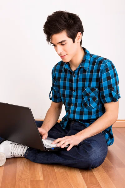 Jeune homme travaillant sur ordinateur portable à la maison — Photo