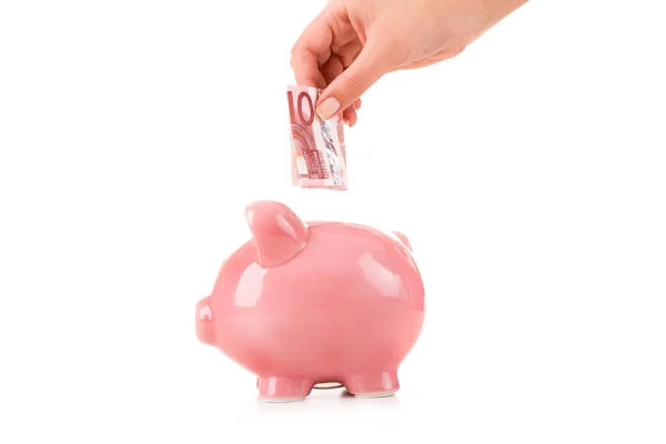 Mano femenina poniendo una moneda en una alcancía — Foto de Stock