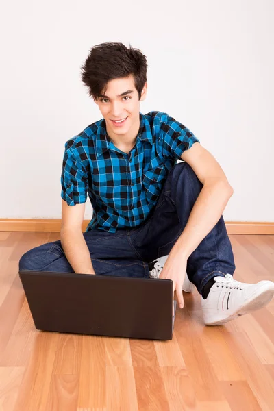 自宅のコンピューターのノート パソコンに取り組んで若い男 — ストック写真